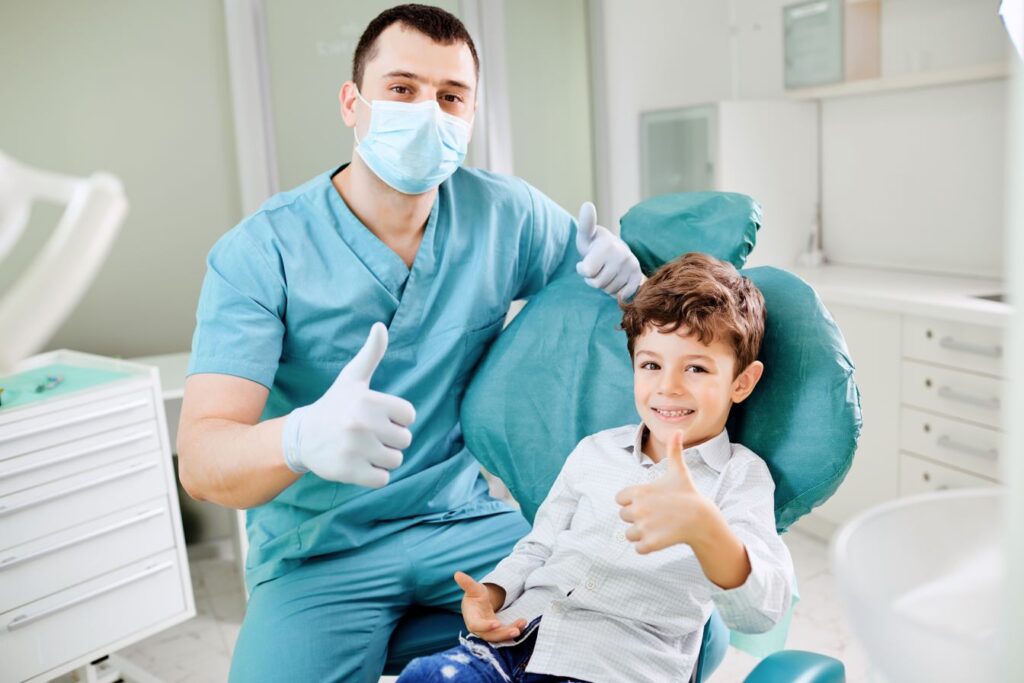 A little boy and a dentist giving thumbs up in a dental exam room
