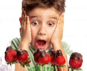 Kid dramatically gasping at a row of chocolate-covered strawberries